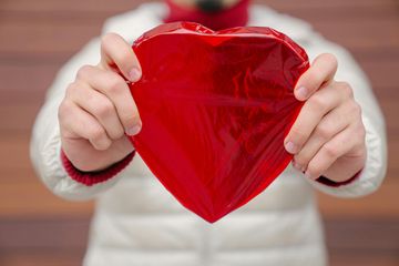 A man is holding a heart showing that he cares of his heart health