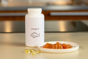 Bottle of Omega-3 supplements for men alongside fresh salmon fillet on a cutting board